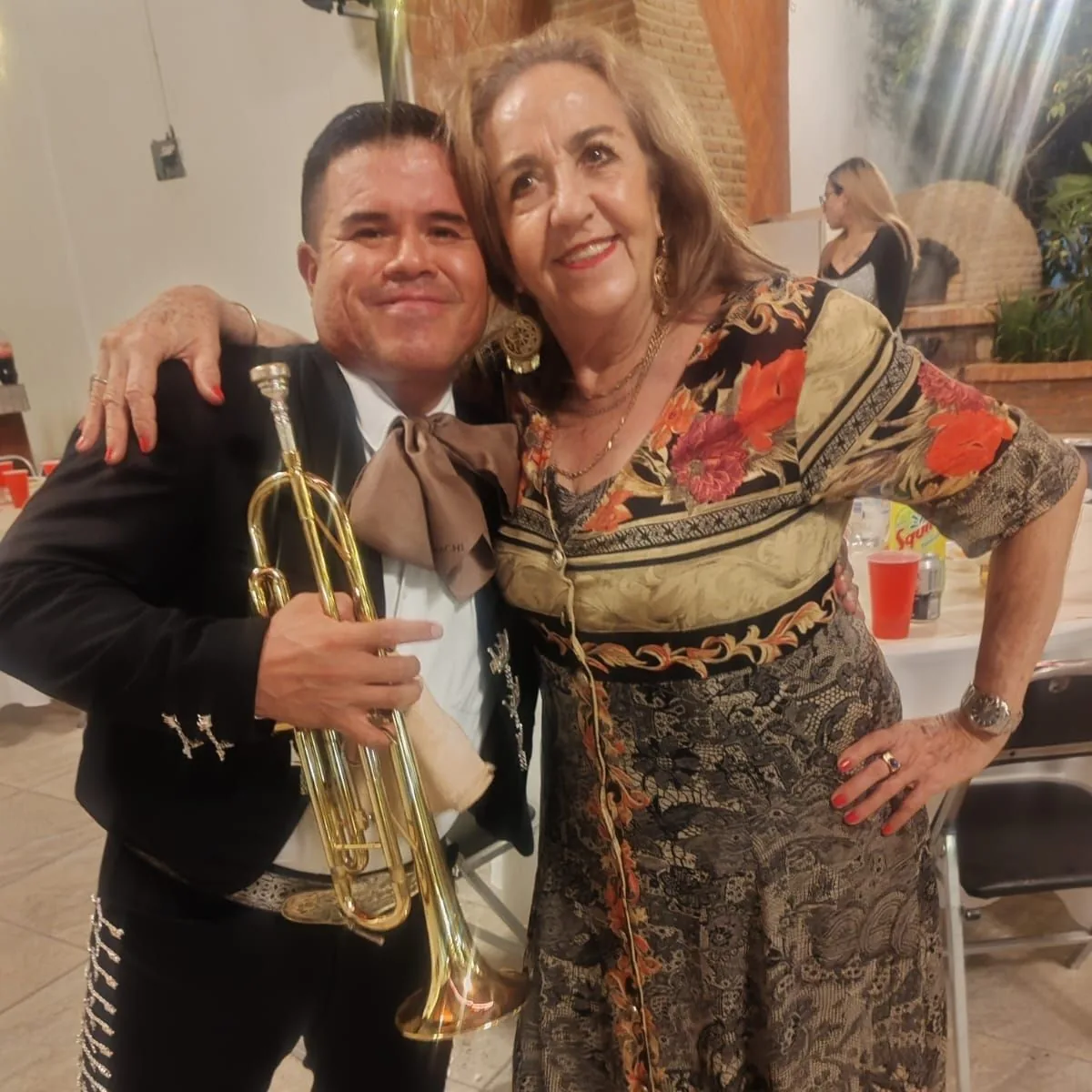 Integrante de Mariachi Los Príncipes con una clienta durante una celebración de aniversario